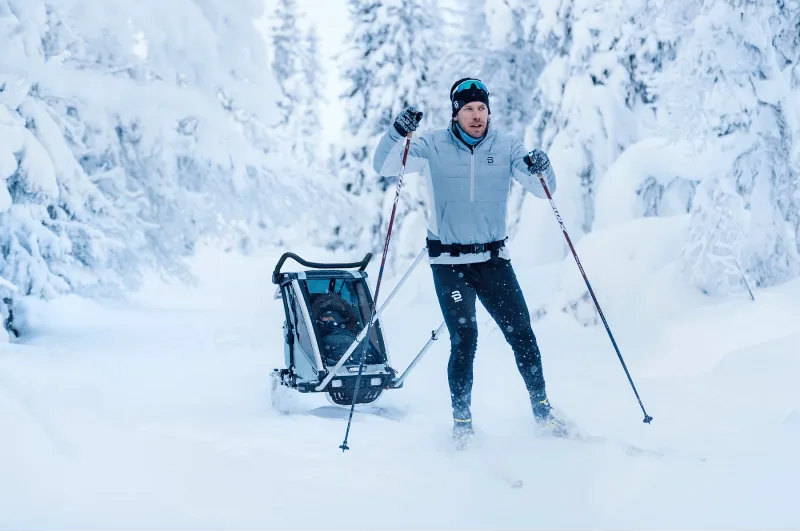 Går på langrennsski med ombygd barnevogn på ski bak seg