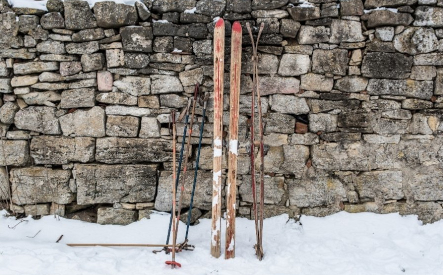 To par skogsski lent mot en steinmur, to par staver ved siden av